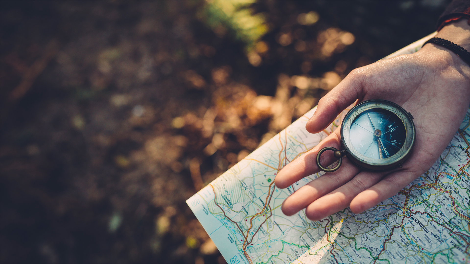 Hand holding compass and map